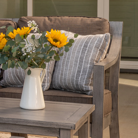 Vase of yellow flowers on outdoor coffee table by sofa from Villa Outdoors