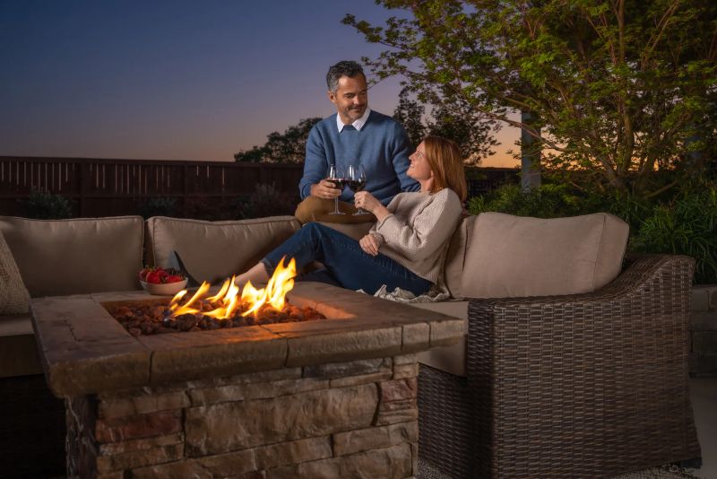Man and woman drinking wine on outdoor sofa by fire pit from Villa Outdoors