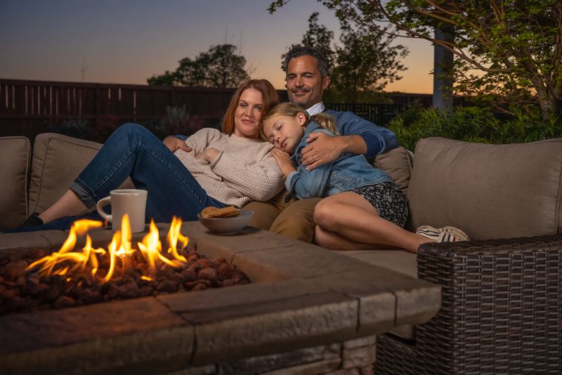 Man and woman with girl sleeping on outdoor sofa by fire pit from Villa Outdoors