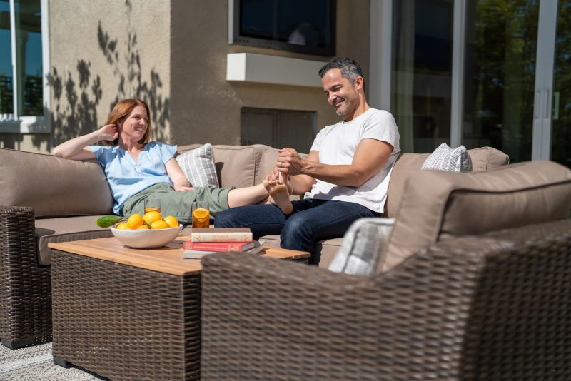 Man rubbing womans feet sitting on wicker outdoor sofa from Villa Outdoors